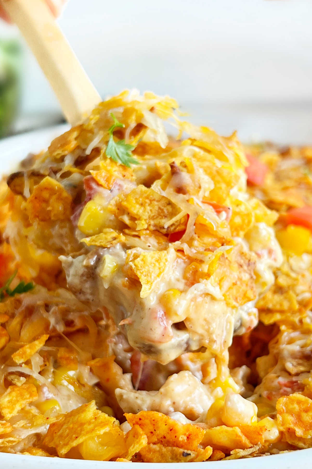 cheesy Dorito chicken casserole with Doritos, corn and tomatoes on a wooden spoon