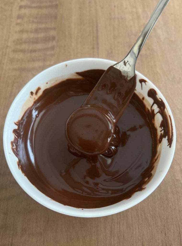 dip banana slices into melted chocolate with fork