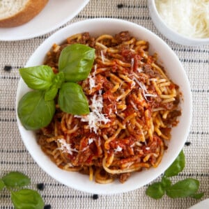 instant pot spaghetti and meat sauce in white bowl with basil and Parmesan