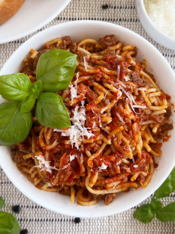 instant pot spaghetti and meat sauce in white bowl with basil and Parmesan