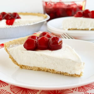 slice of no bake cheesecake with cool whip and cream cheese on graham cracker crust with cherry topping