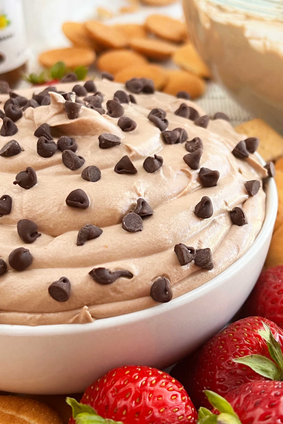 bowl of Nutella cheesecake dip with mini chocolate chips with strawberries and vanilla wafer cookies.