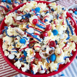 patriotic popcorn with red white and blue m and m candy and melted candy coating in red bowl