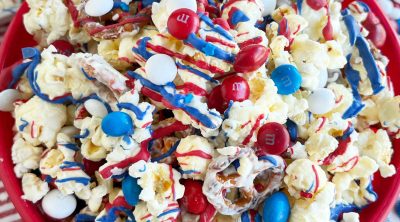 patriotic popcorn with red white and blue m and m candy and melted candy coating in red bowl