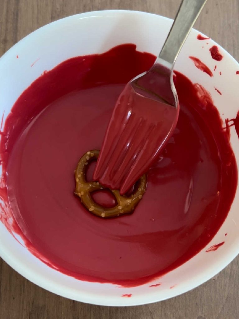 dip mini pretzel into melted red candy coating