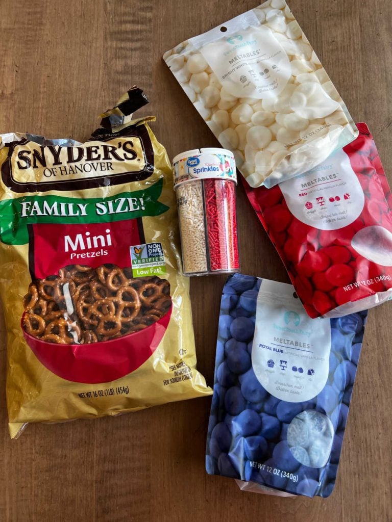 mini pretzels, red white and blue candy melts and patriotic sprinkles on a table.