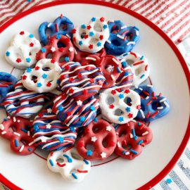 red white and blue pretzels with patriotic sprinkles on a red and white plate.