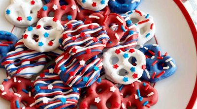 red white and blue pretzels with patriotic sprinkles on a red and white plate.