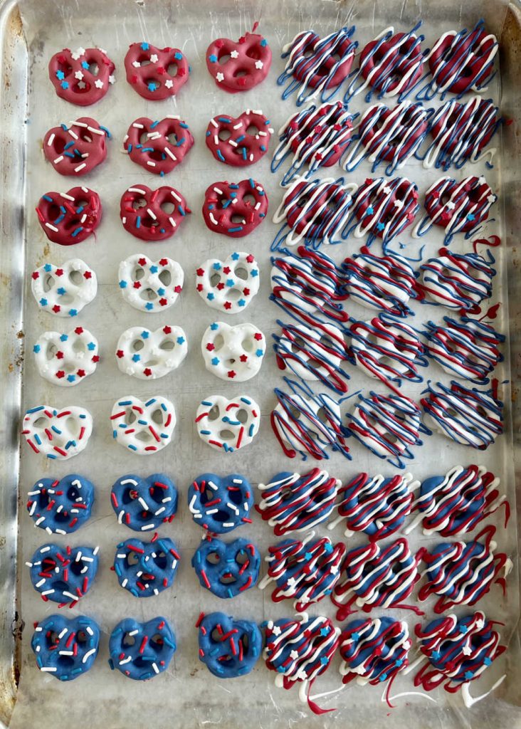 decorated red white and blue patriotic pretzels on wax paper baking sheet.