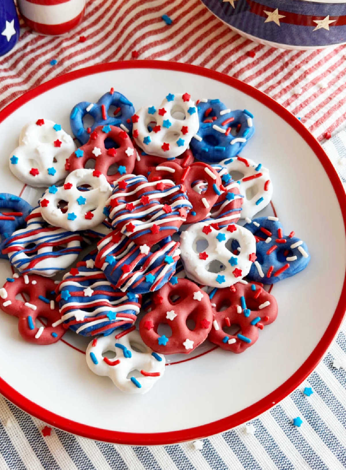 red white and blue chocolate covered pretzels with patriotic sprinkles on 4th of July table.