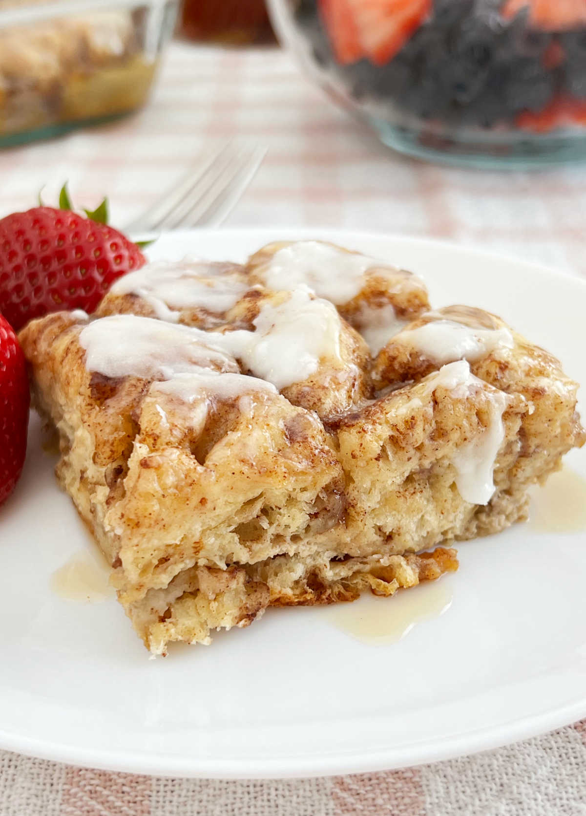 piece of cinnamon roll casserole on plate with strawberries