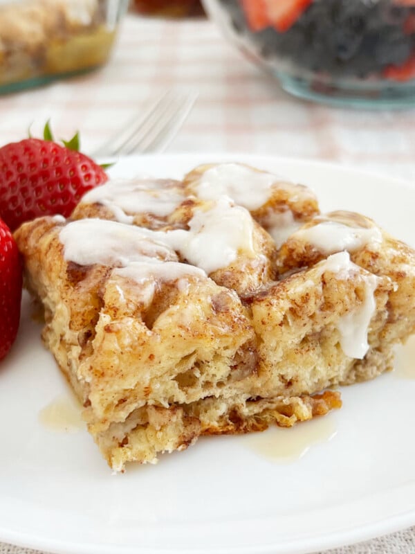 cinnamon roll casserole with cream cheese frosting and maple syrup on plate