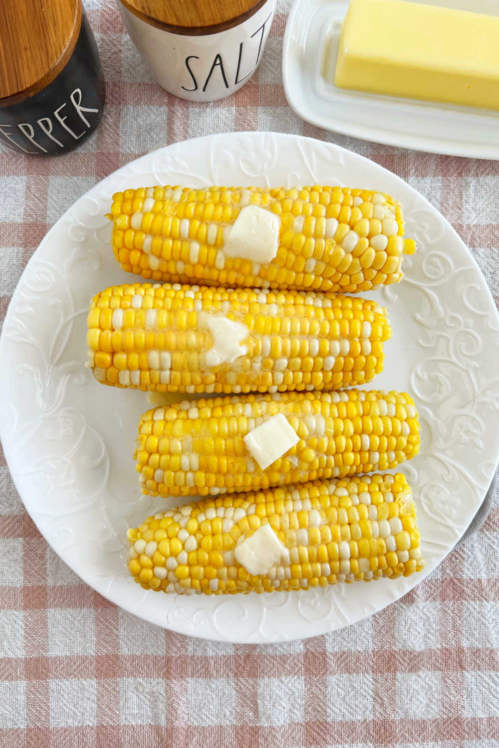 plate of corn on the cob with butter on the table.