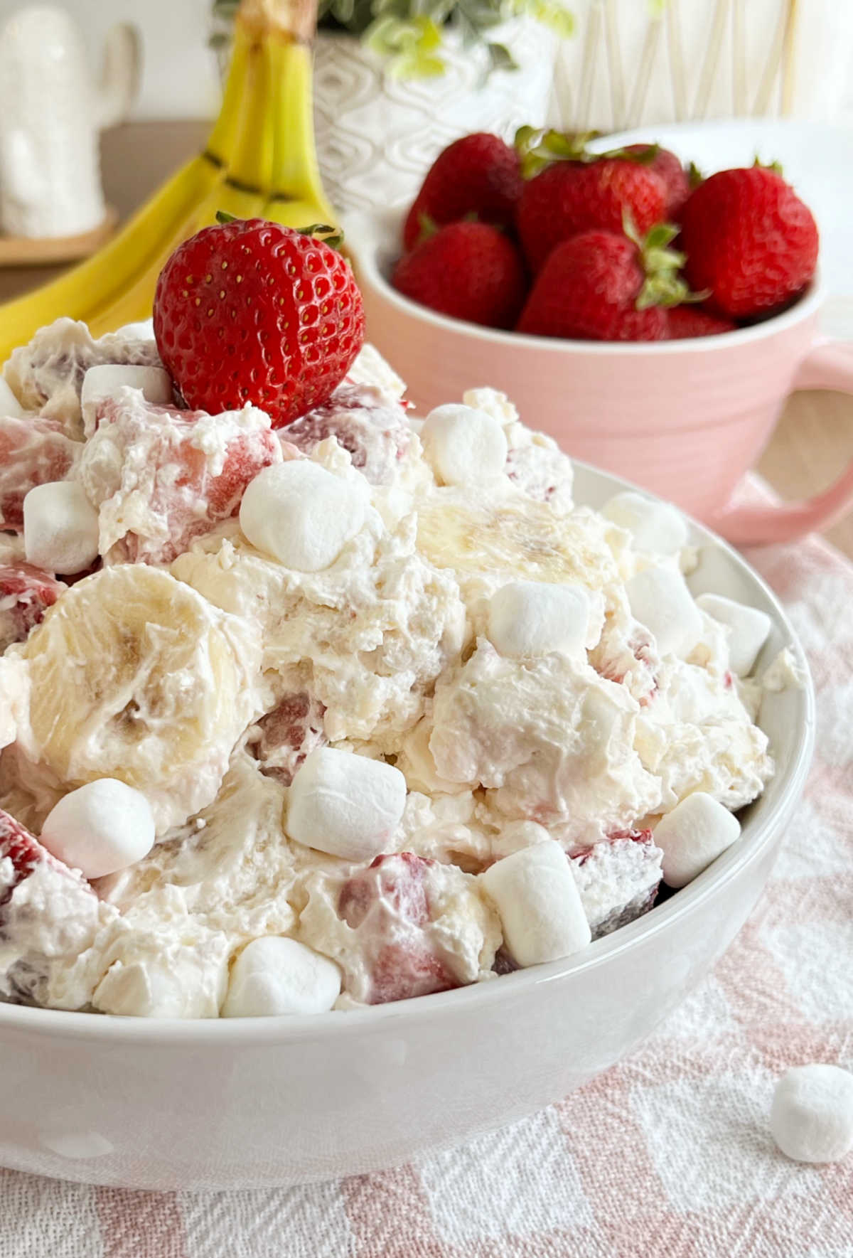 creamy strawberry banana cheesecake salad in white bowl on talbe