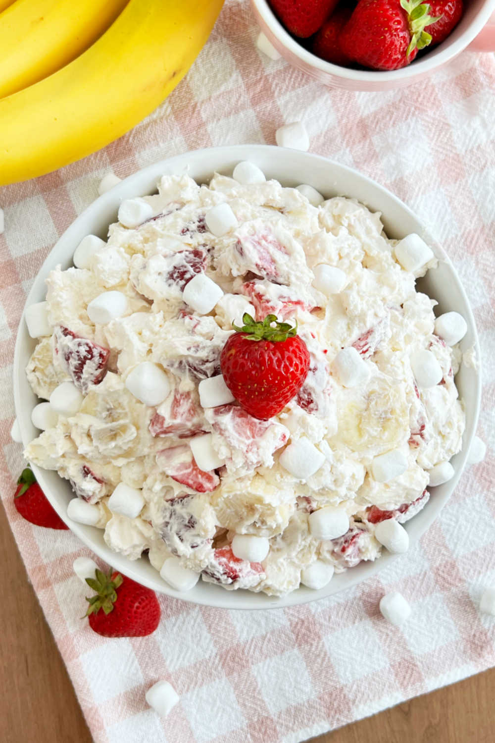 easy strawberry banana cheesecake salad topped with fresh strawberry and mini marshmallows in serving bowl