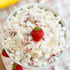 strawberry banana cheesecake salad in white bowl with marshmallows