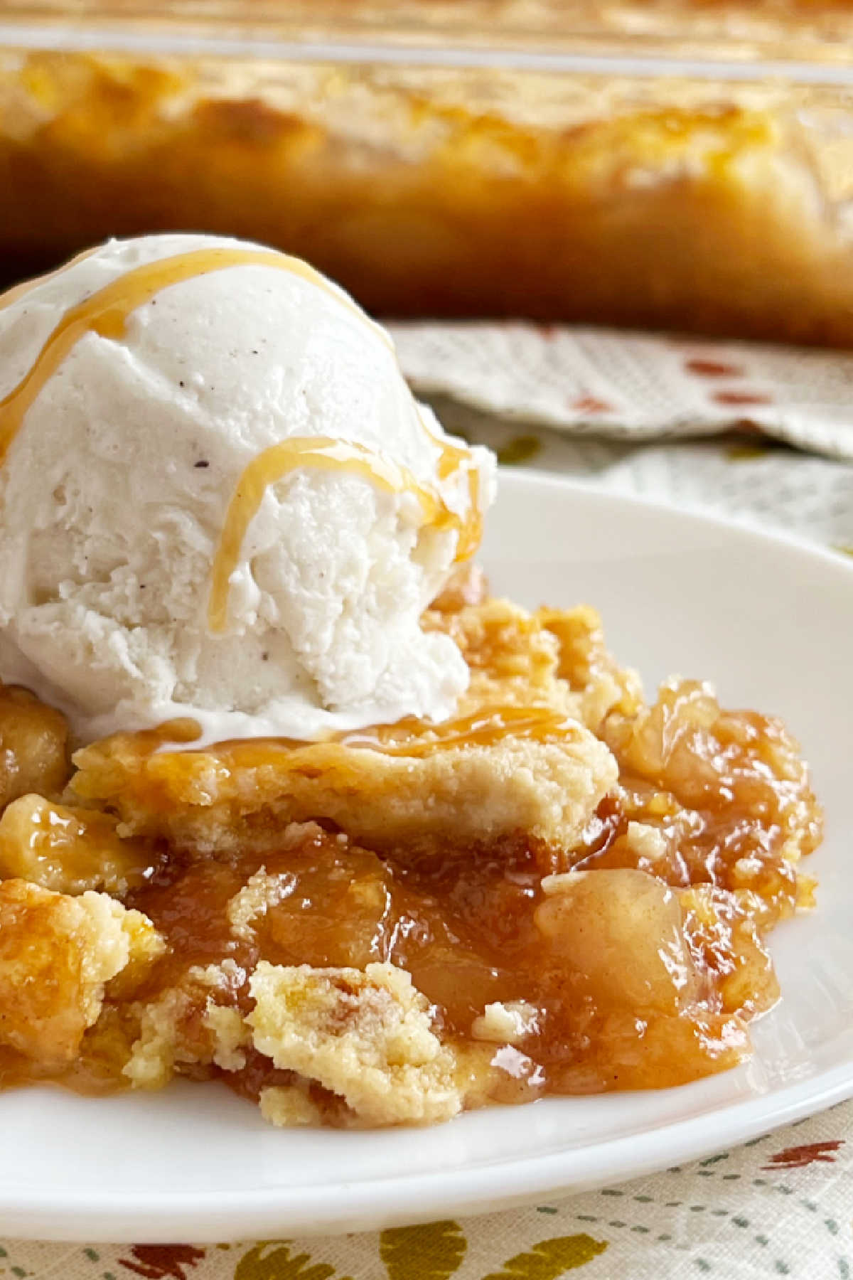 close up of caramel apple pie dump cake on plate with ice cream.