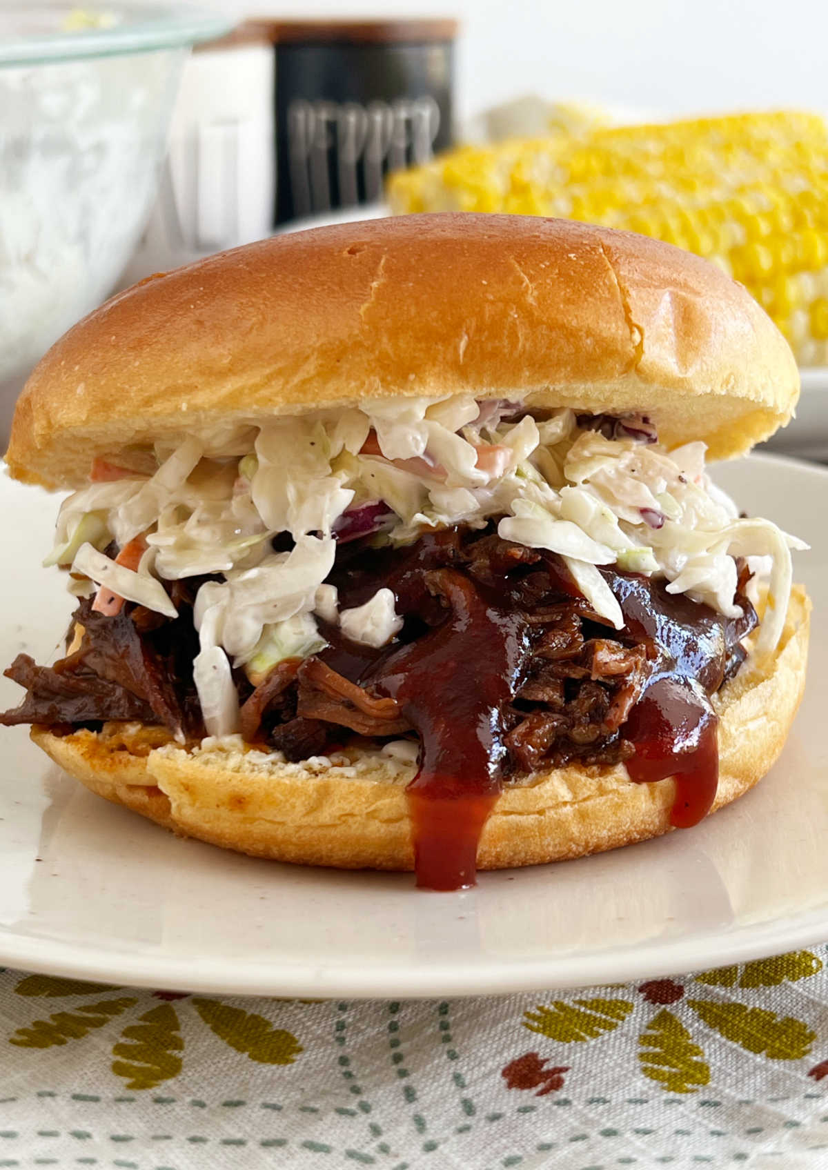slow cooker bbq beef sandwich with coleslaw and bbq sauce on plate.