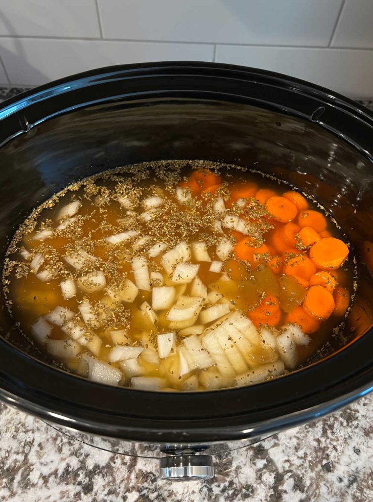 chopped onions, carrots and chicken broth in slow cooker.