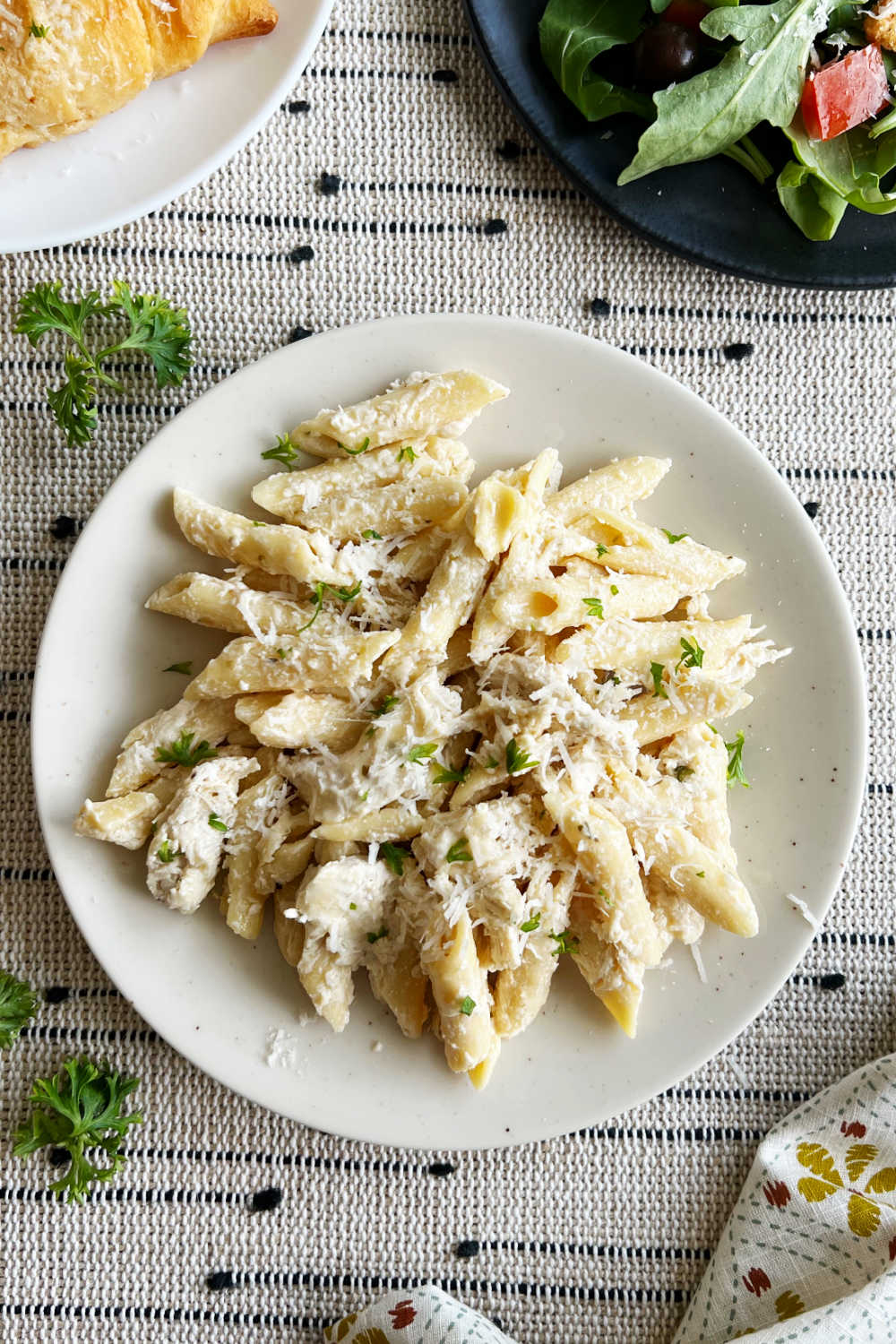 plate of olive garden chicken pasta with bread sticks and salad.