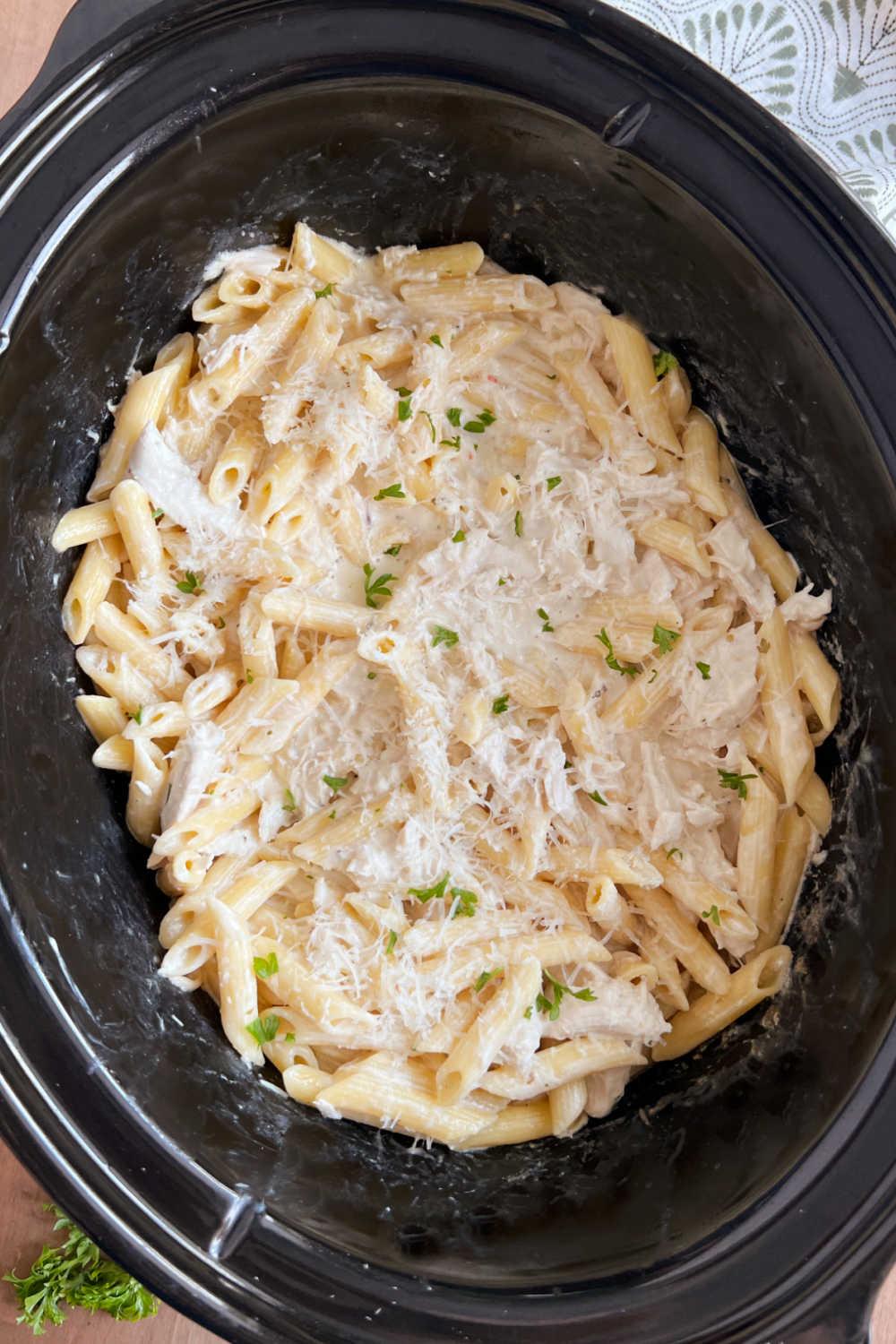 olive garden crockpot chicken pasta with parsley in slow cooker.