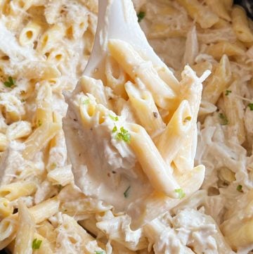 crock pot olive garden chicken pasta in creamy sauce on serving spoon in slow cooker.