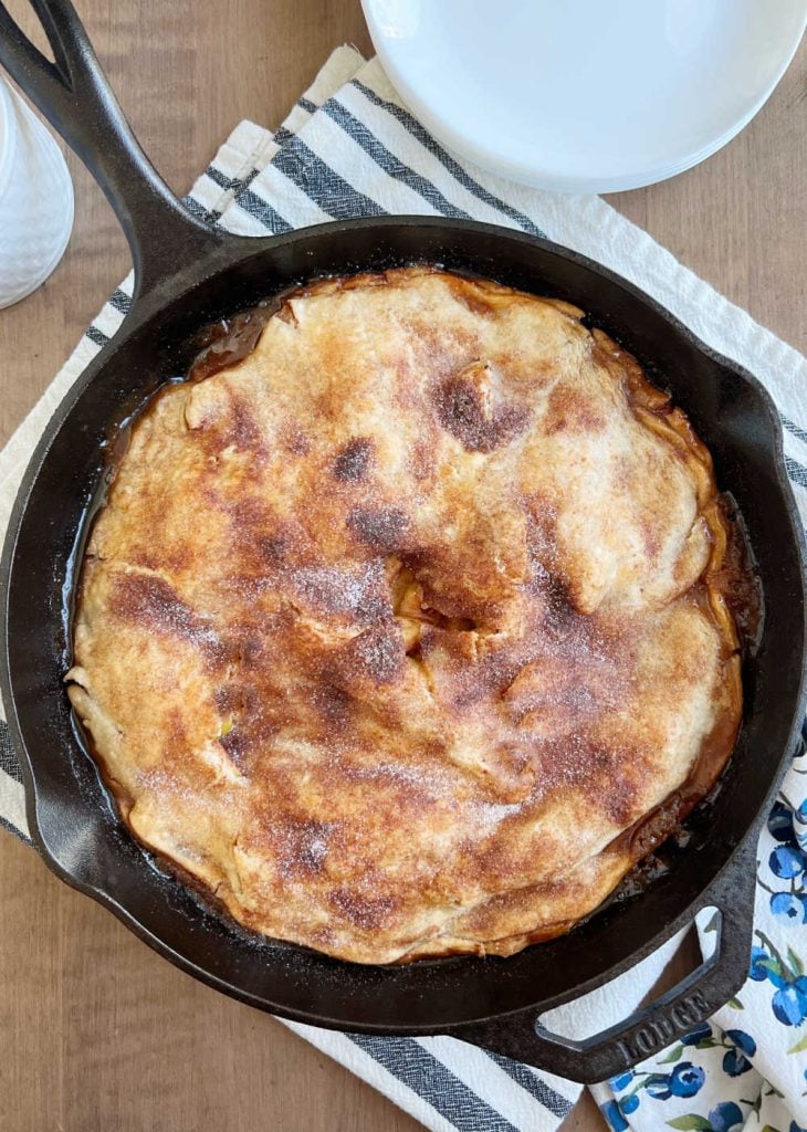 apple pie baked in cast iron skillet on the table.