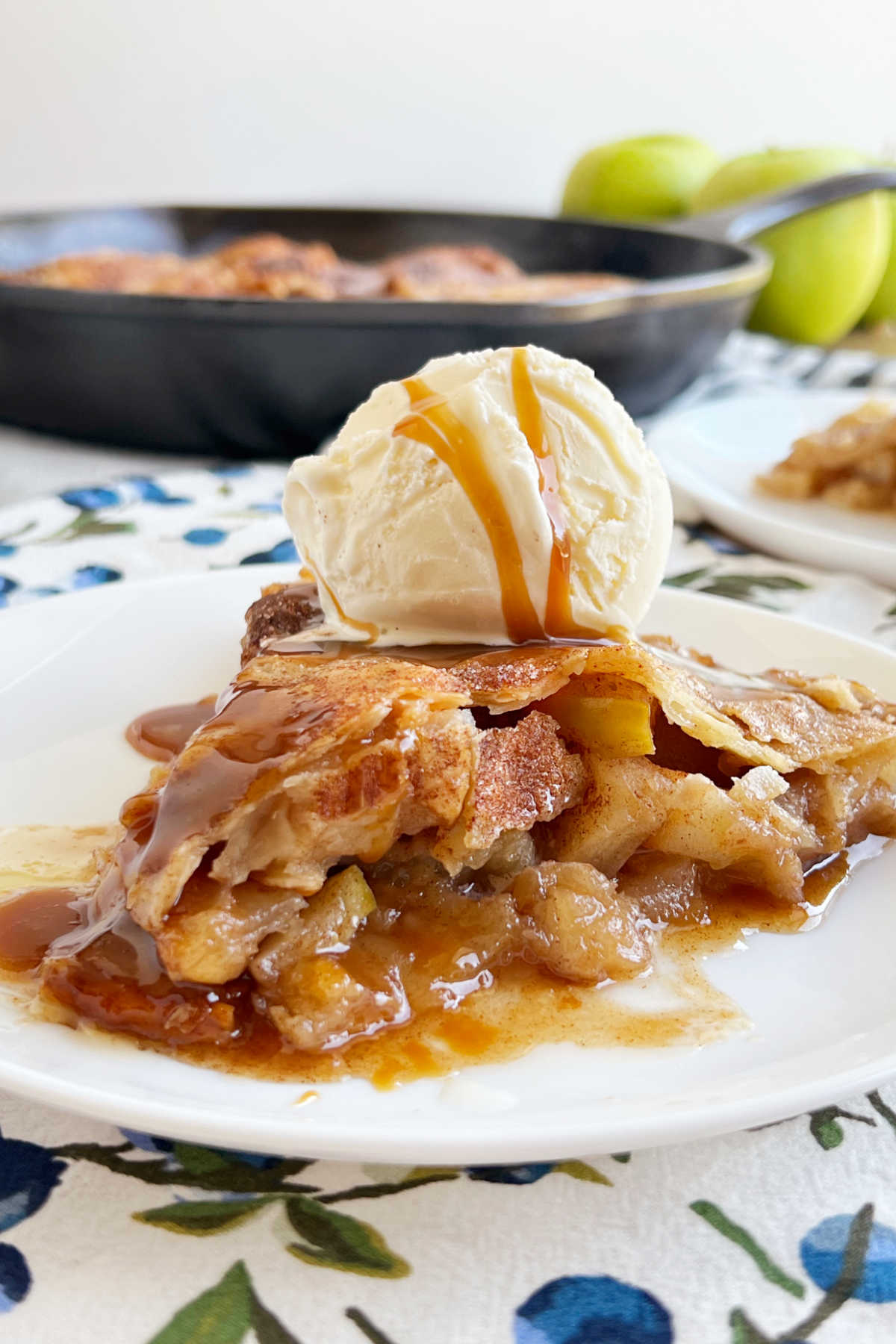 slice of cast iron skillet apple pie with scoop of ice cream on plate.