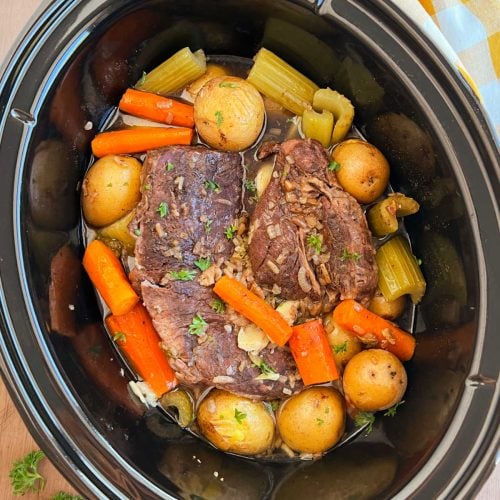 slow cooker pot roast with onion soup mix, potatoes and carrots in crock pot.