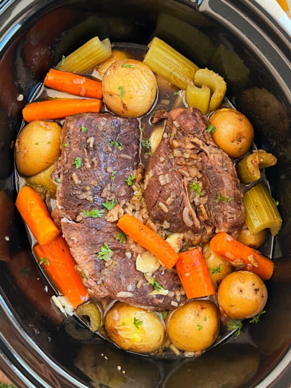 slow cooker pot roast with onion soup mix, potatoes and carrots in crock pot.