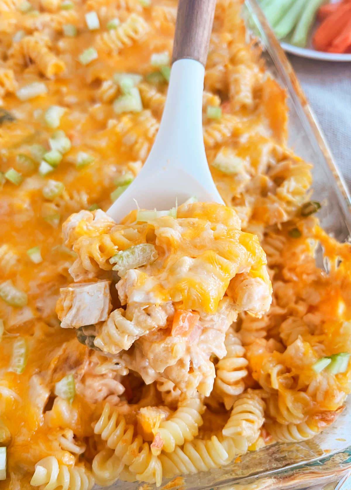 buffalo chicken casserole with pasta and veggies in a creamy cheese sauce on spoon.