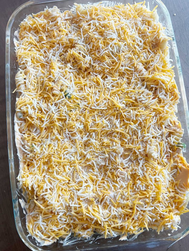 shredded cheese on top of chicken casserole in baking pan.