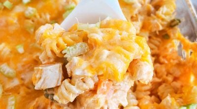 buffalo chicken casserole with pasta and vegetables on serving spoon.