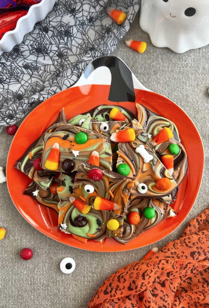 Halloween bark with candy corn and Halloween candy on a pumpkin plate.