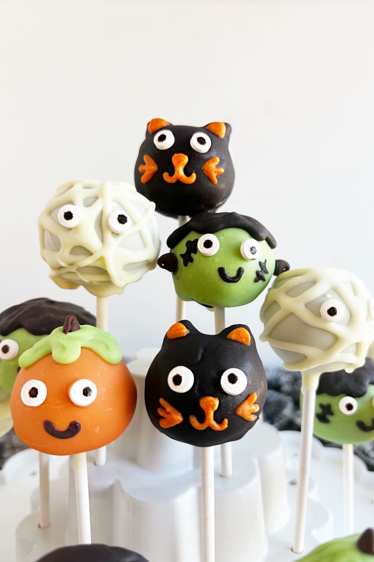 Halloween cake pops decorated as cat, mummy, pumpkin and Frankenstein.