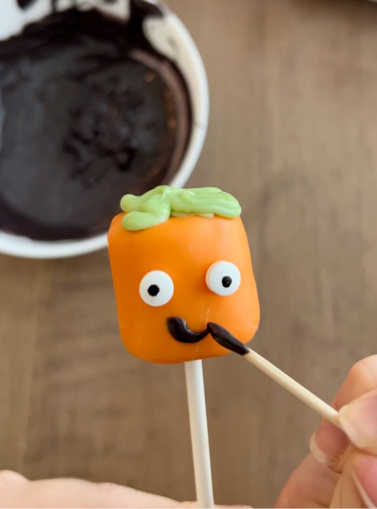 decorate jack-o-lantern marshmallow pop with toothpick.