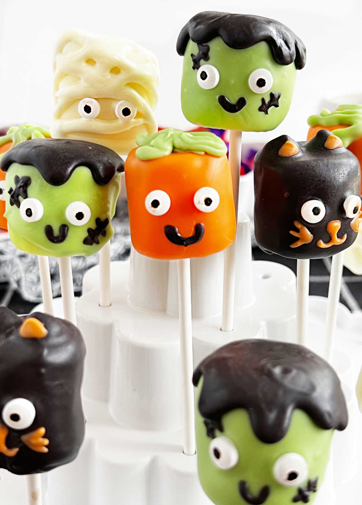 Mummy, black cat, pumpkin and Frankenstein Halloween marshmallow pops on lollipop sticks.