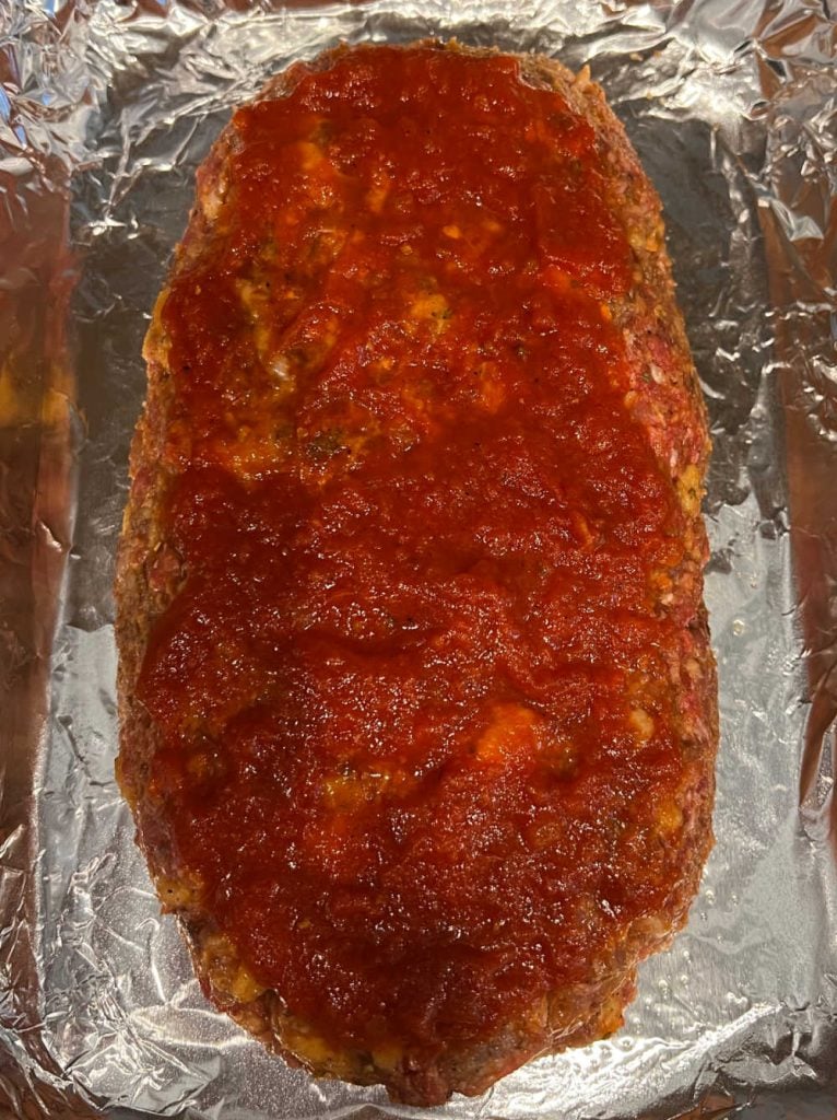 meatloaf topped with marinara sauce in baking pan.
