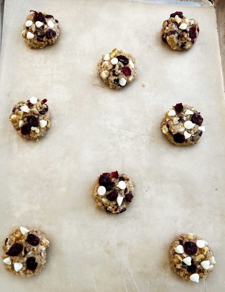 cranberry oatmeal cookie dough on baking sheet with white chocolate chips.