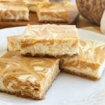 swirled pumpkin cheesecake bars with graham cracker crust on a plate.
