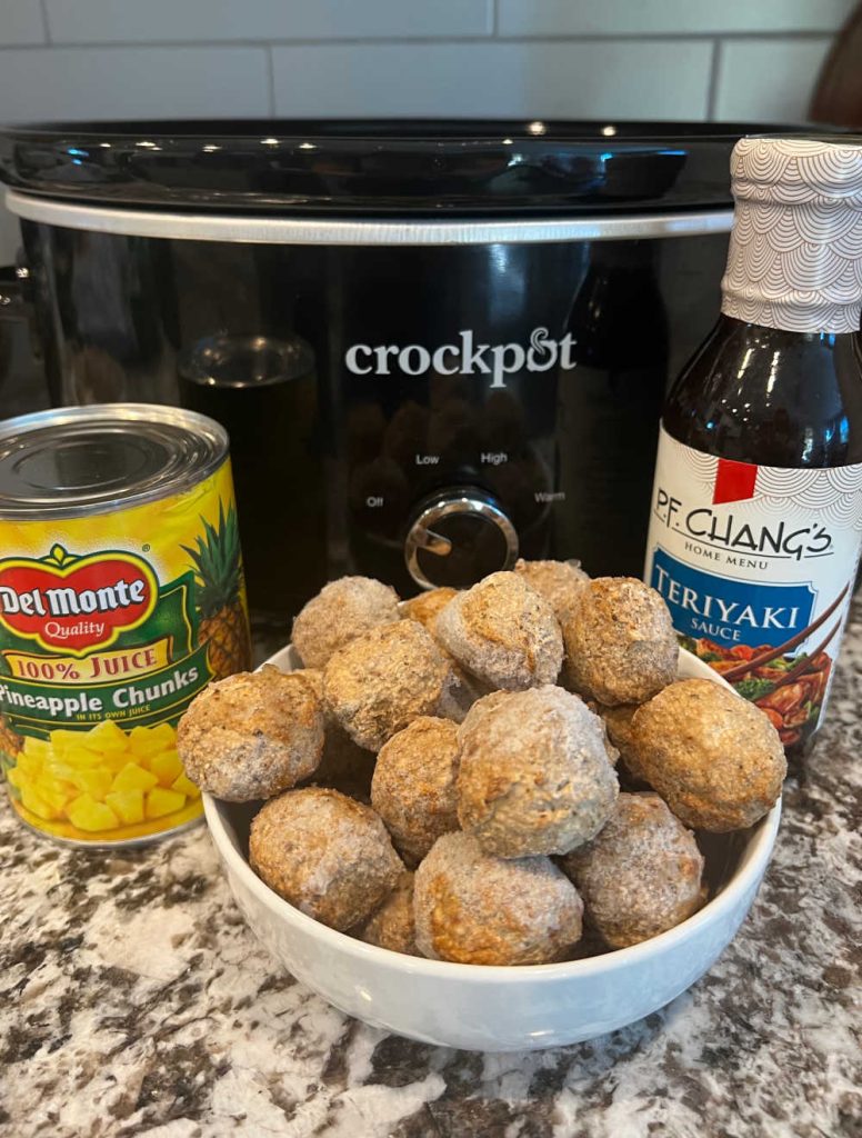 frozen meatballs, can of pineapple chunks and bottle of teriyaki sauce by crockpot.
