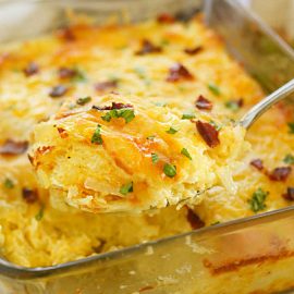 cheesy hashbrown casserole with bacon on serving spoon.
