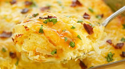 cheesy hashbrown casserole with bacon on serving spoon.
