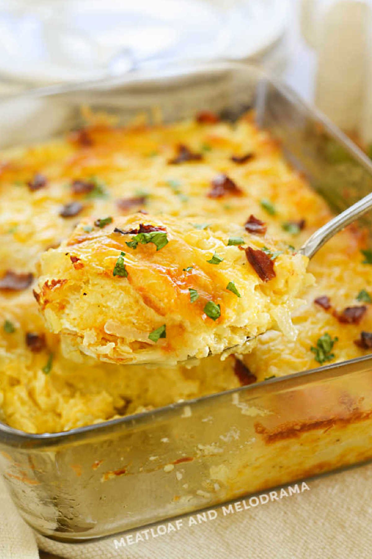 cheesy hashbrown potatoes with bacon on serving spoon.
