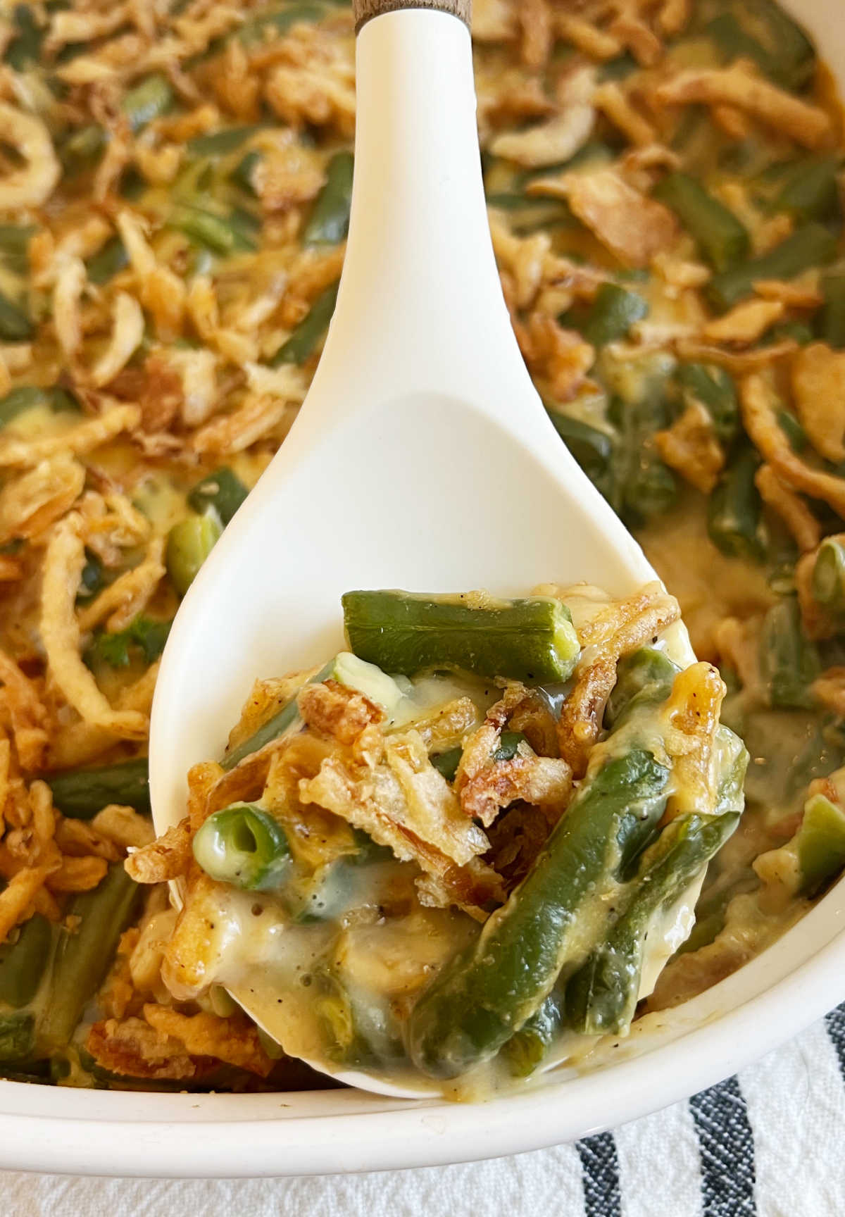 campbells green bean casserole on white serving spoon.