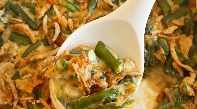 campbell's green bean casserole with fried onions on serving spoon.