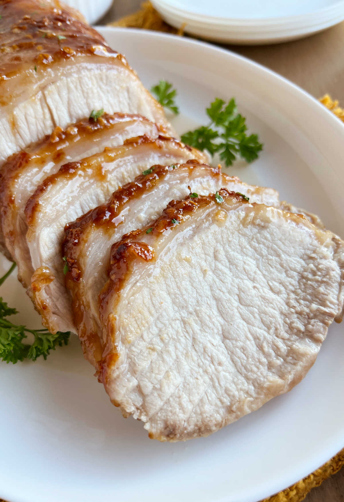 roast pork with maple and mustard glaze sliced on a platter with parsley.