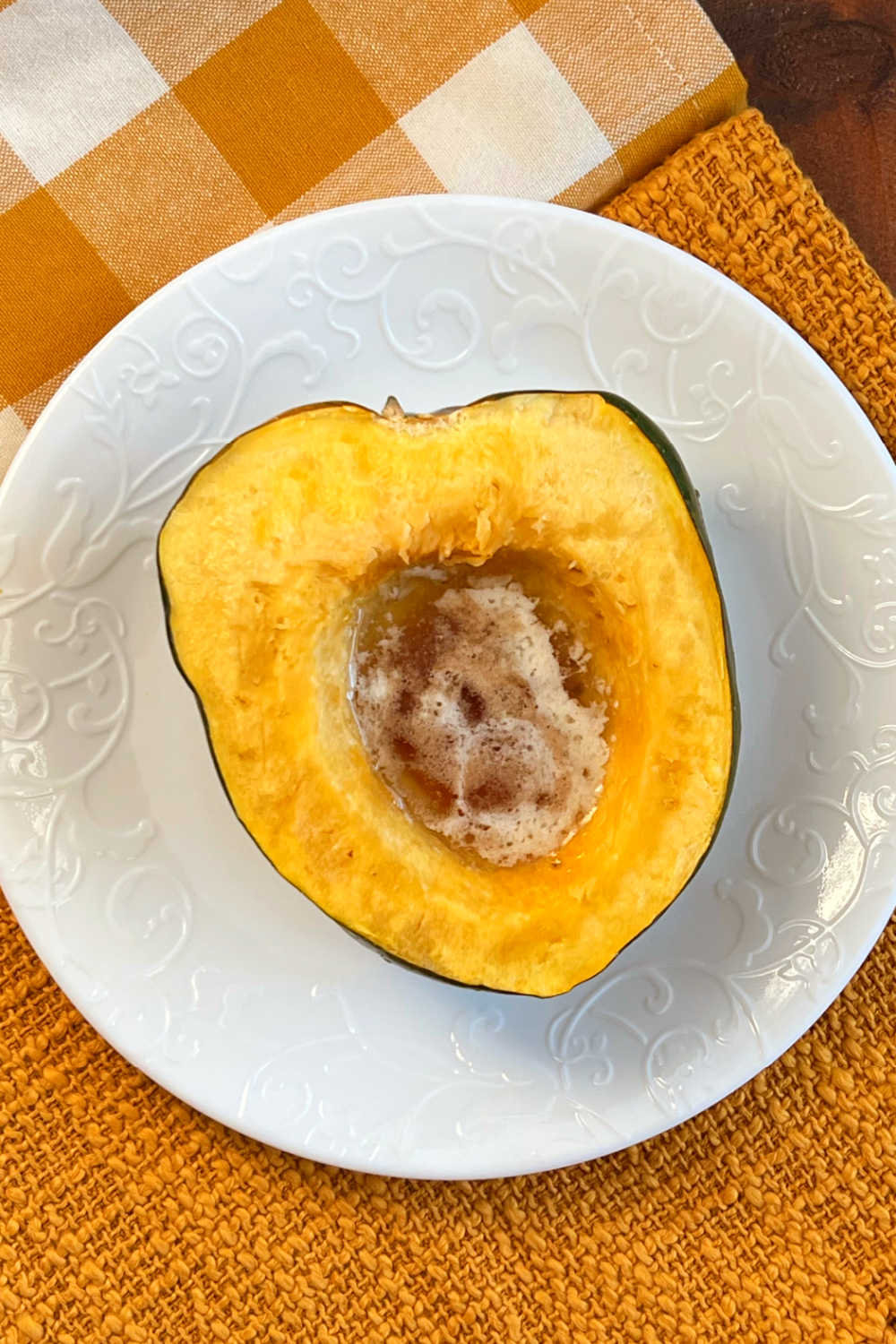 microwave acorn squash half with melted butter and brown sugar on plate.