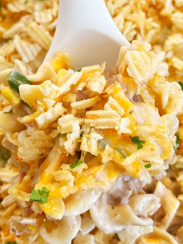 tuna casserole with potato chips and cheese on serving spoon.