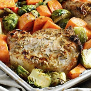 maple mustard pork chops with sweet potatoes and brussels sprouts on sheet pan.